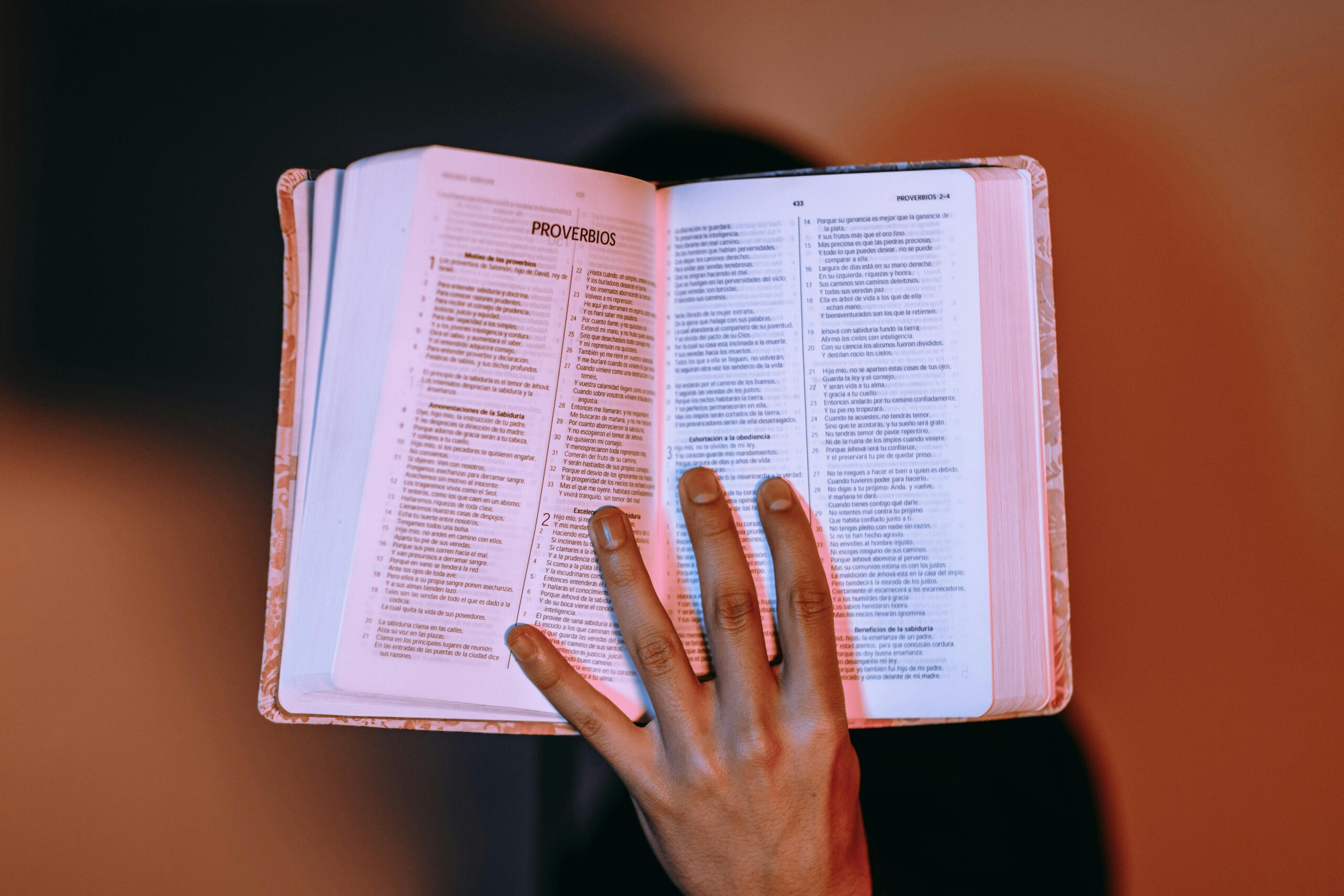 Manos sosteniendo una Biblia abierta con luz suave