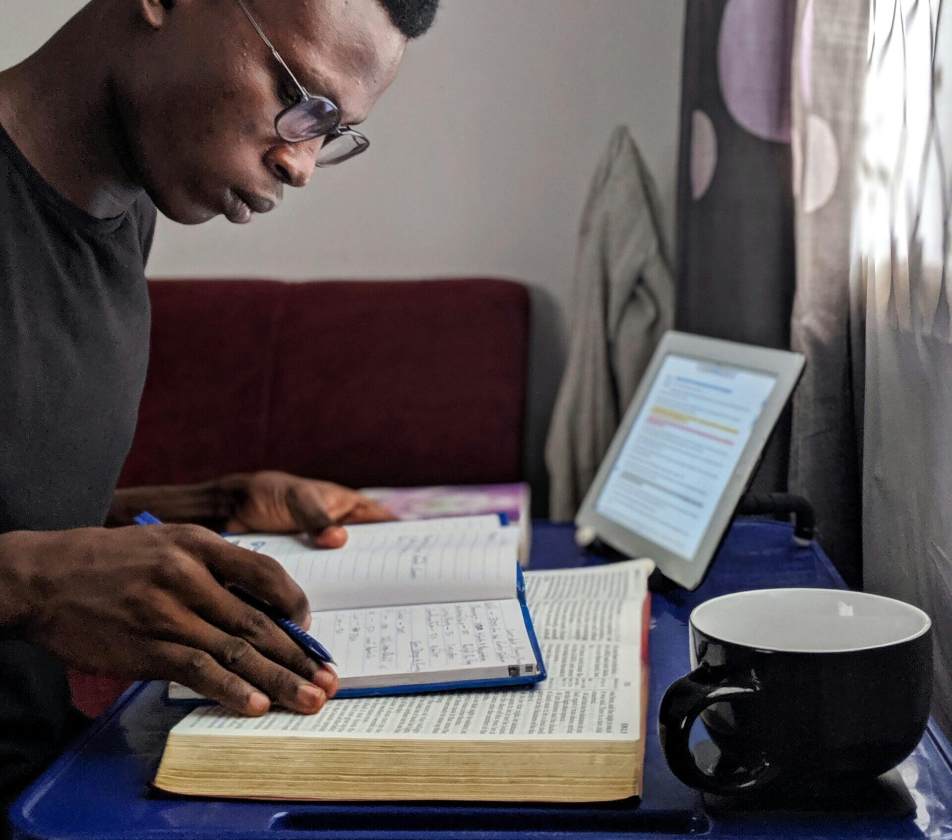 Persona con una Biblia abierta mirando por la ventana, reflexionando